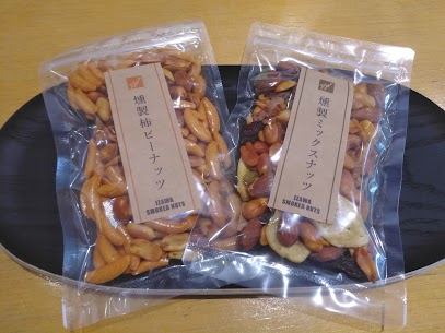 新商品✨ 「燻製柿ピーナッツ」。スモーキーな香り、ついつい手が止まらなくなる美味しさ😋 お酒のお供に、おやつに。「燻製ミックスナッツ」ナッツ本来の甘みとコクに、深みのある香りが加わりワンランク上の味わい✨
